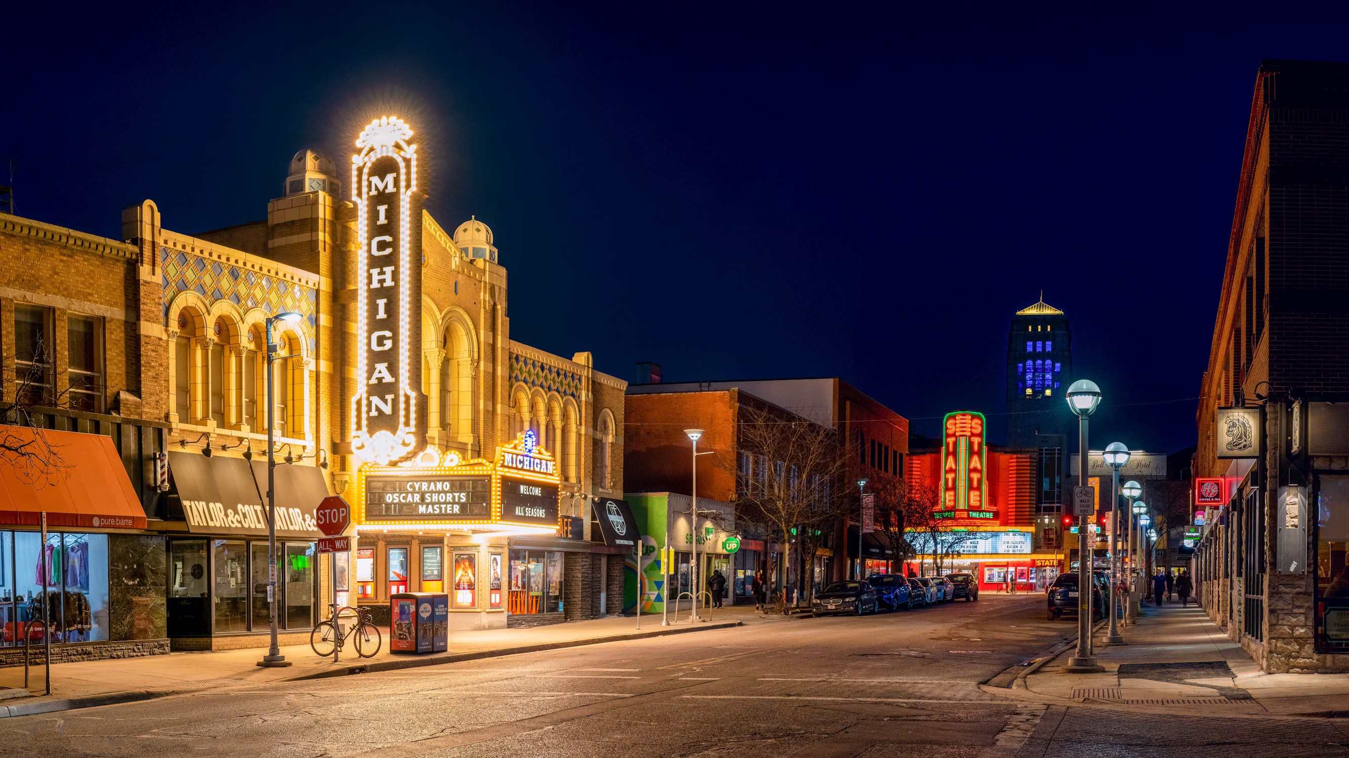 Downtown Ann Arbor at night — the Michigan Theater marquee glowing on Liberty Street, with Burton Tower visible in the distance